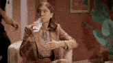 a woman in a suit is drinking water from a bottle