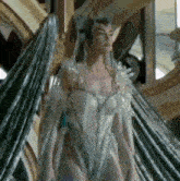 a woman in a white dress with wings and a crown is standing in front of a mirror .