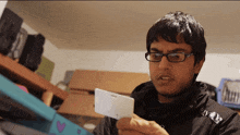 a man wearing glasses is holding a white card