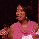 a woman in a pink sweater holds a glass of wine