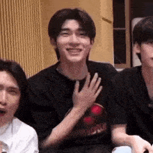 a group of young men are sitting next to each other in a room and smiling .