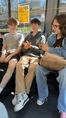 a group of young men are sitting on a bus looking at their cellphones