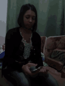 a woman is sitting on a couch looking at her cell phone