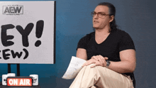 a man sits in front of a sign that says ey