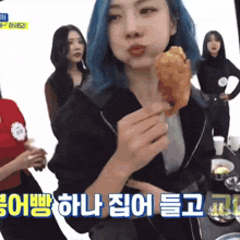 a woman with blue hair is holding a fried chicken wing in her hand