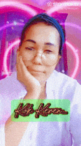 a woman wearing glasses and a headband has her hand on her face in front of a sign that says ' kop keren '