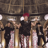 a group of young men are dancing in front of a stained glass window with a crown on it