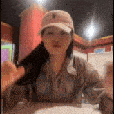 a woman wearing a baseball cap is sitting at a table in a restaurant .