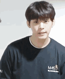 a young man wearing a black shirt with the word mis on it is making a funny face .