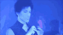 a man is singing into a microphone in a dark room with a blue light behind him .
