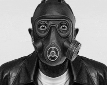 a black and white photo of a man wearing a gas mask and a leather jacket