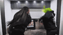 a woman in a green wig is standing next to a man in a black hoodie that says zeus on the back