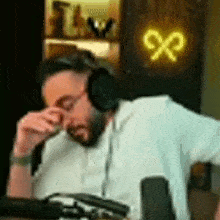 a man wearing headphones is sitting in front of a microphone and covering his eyes .