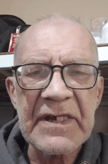 a man with glasses and a beard looks at the camera with a bag of red bull in the background