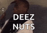 a man in a robe is sitting on a couch holding a glass of water and saying deez nuts .