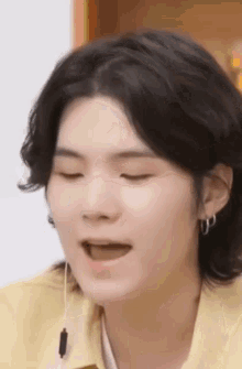 a close up of a person 's face with their eyes closed and a yellow shirt on .