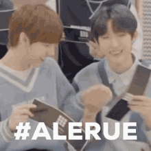 a couple of young men are sitting next to each other holding a book and smiling .