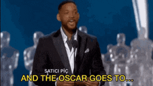 a man in a suit is speaking into a microphone and the oscar goes to