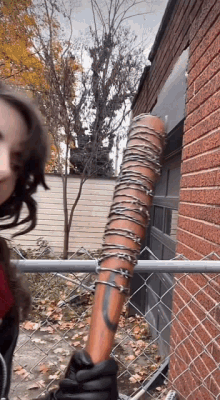 a woman is holding a baseball bat with barbed wire on it .