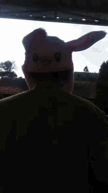 a man wearing a pink bunny hat with a smiling face on it