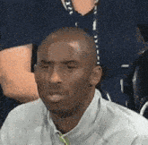 a man in a white shirt and tie is sitting in a stadium looking at the camera .