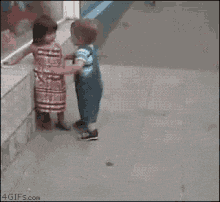 a boy and a girl are fighting on the sidewalk
