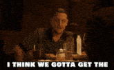 a man sits at a table with a glass of beer and the words i think we gotta get the
