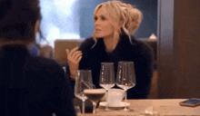 a woman sitting at a table with wine glasses
