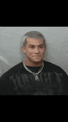 a man wearing a black shirt and a necklace is making a funny face .