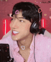 a young man wearing headphones and a pink shirt