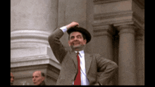 a man in a suit and tie is holding his hat up
