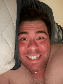 a man laying on a bed with a pillow covering his face