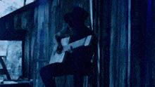 a man is sitting on a chair playing a guitar in front of a wooden building .