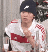a person wearing an adidas shirt and a beanie with the letter p on it