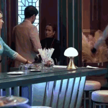 a man and a woman are standing at a table with a lamp on it