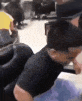 a man in a black shirt is sitting in a chair with his head on a table .