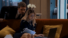 a man and a woman are sitting on a couch with a laptop