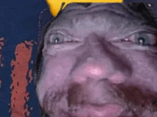 a close up of a man 's face with a beard and a yellow hat .