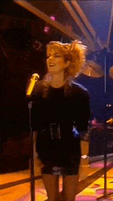 a woman is singing into a microphone on a stage