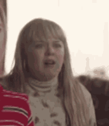 a woman is sitting on a couch with her mouth open and making a funny face .