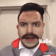 a man with a mustache is making a funny face while wearing a jacket .