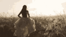 a woman in a long white dress is standing in a field .