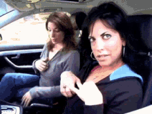 two women are sitting in a car one is looking at the camera