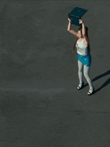 a woman in a white tank top and blue shorts is standing on a concrete surface