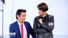 a man and a woman are standing next to each other and the woman is wearing a leather jacket