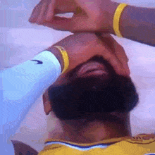 a man with a beard is covering his face with his hands .