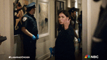a woman standing in a hallway with a nbc logo on the bottom
