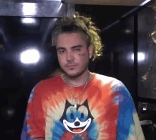 a man wearing a colorful tie dye shirt with a cat on it .
