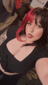 a woman with red hair and black hair is taking a selfie while sitting on a couch .