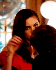 a woman in a red dress is kissing a man in a black suit